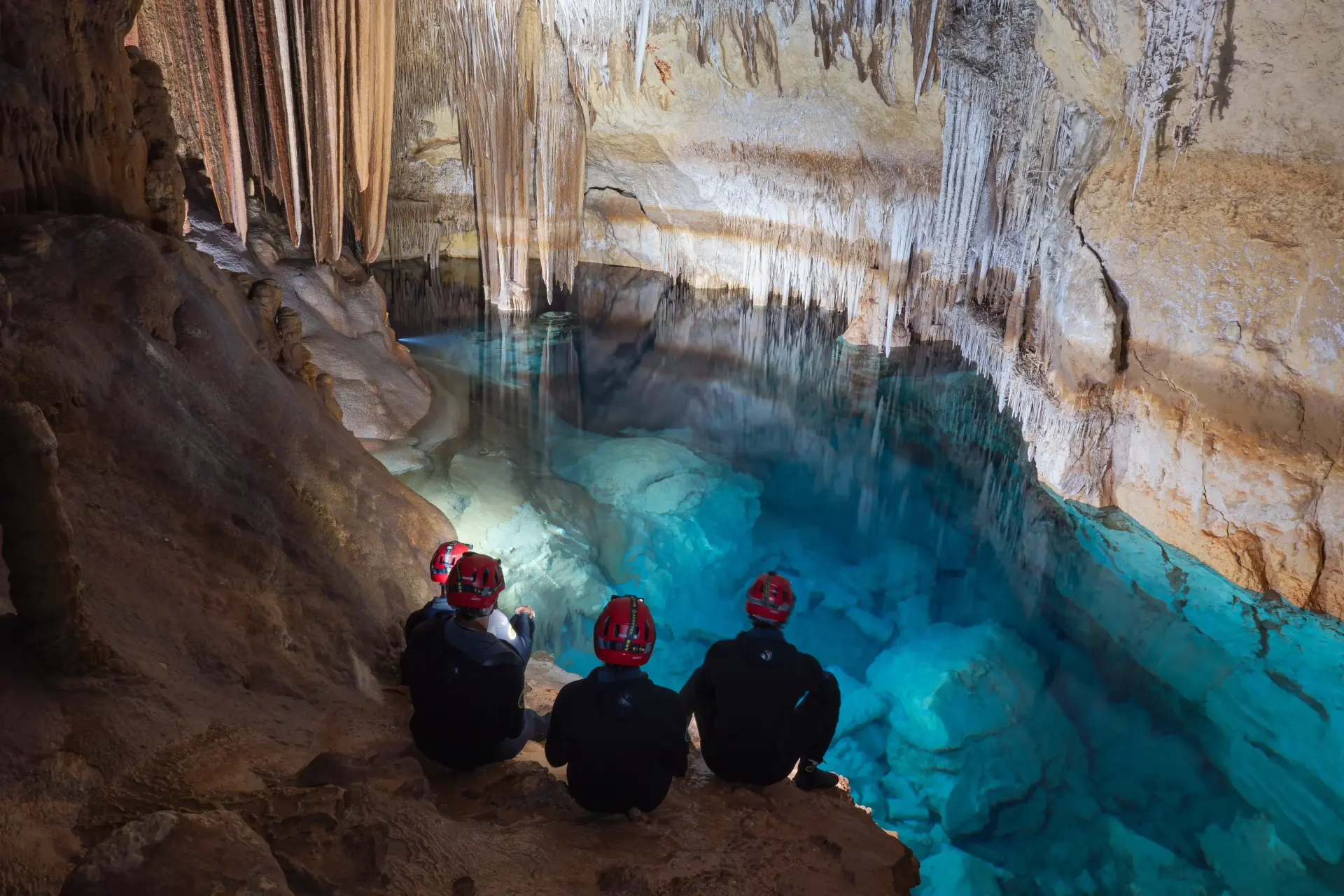 Explorers beside a blue underground lake in a sea cave